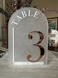 Table number 3 on a stone pedestal with decorative elements in the background