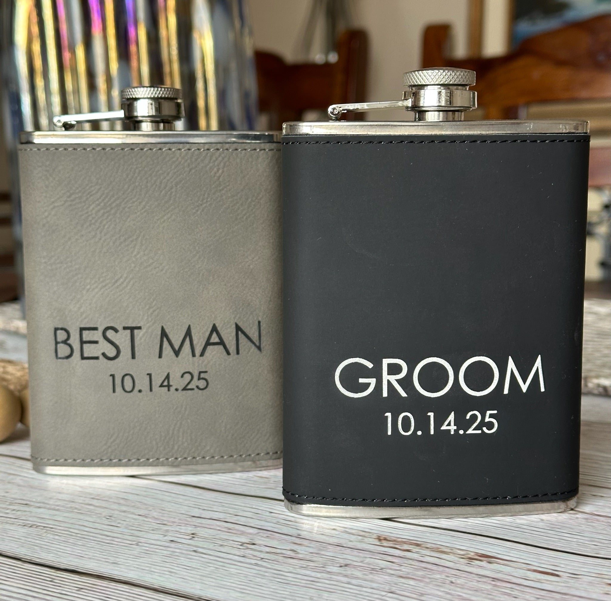 Two flasks, one labeled 'Best Man' and the other 'Groom', on a wooden surface.