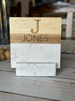 Wooden and marble card holder with 'JONES' engraved on a wooden surface.