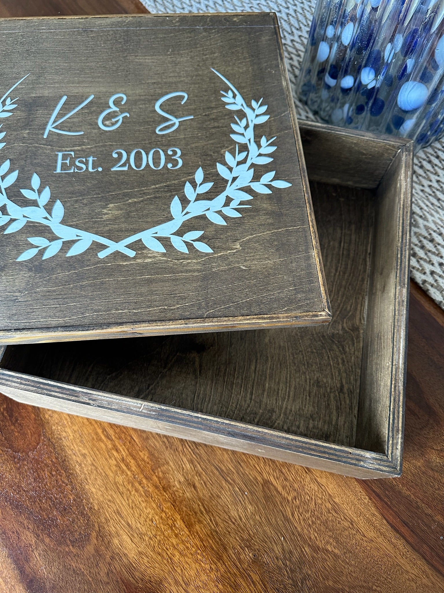 Wooden box with engraved initials and year on a wooden surface