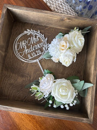 Floral corsages with 'Mr & Mrs Anderson' sign in a wooden box.