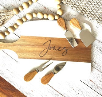 Wooden cutting board with engraved name 'Jones' and cheese tools on a wooden surface.