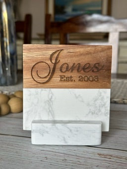 Wooden and marble name card holder with 'Jones Est. 2008' engraving on a wooden surface.