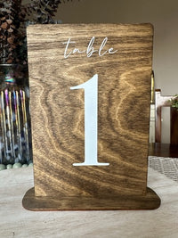 Wooden table number holder with 'table 1' on a wooden surface.