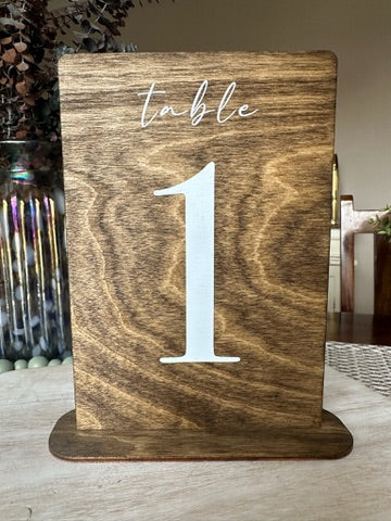 Wooden table number holder with 'table 1' on a wooden surface.